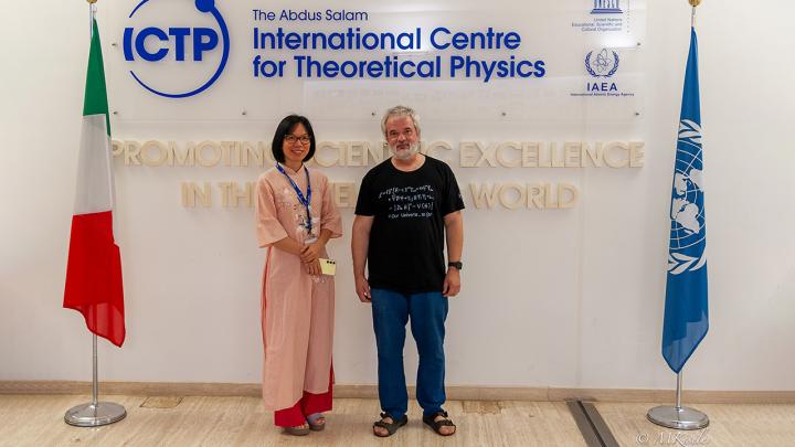 Nguyen Thi Kim Thanh and Mikhail Kiselev posing in front of the ICTP logo