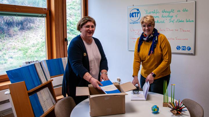 ICTP Head Librarian Eva Babonich (right) and colleague Dora Tirana preparing a shipment of book donations.